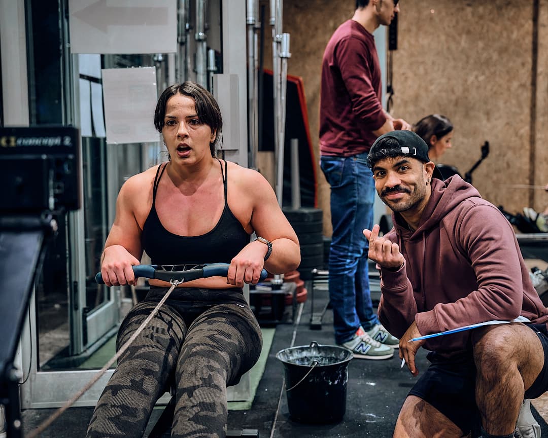 Coach CrossFit et Hyrox encourageant une athlète sur rameur pendant un WOD à Paris 13 Rive Gauche